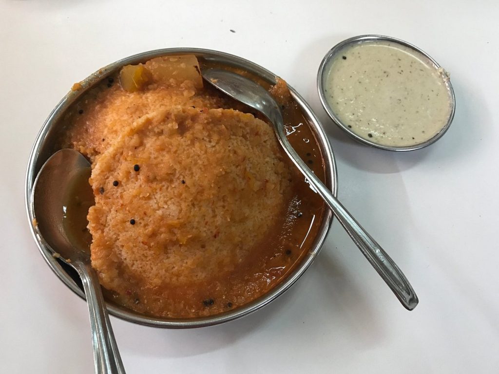 A bowl of idli and sambar paired with coconut chutney in separate bowl